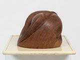 a wooden sculpture on top of a white pedestal