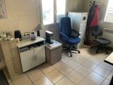 a desk with a chair and a refrigerator in a room