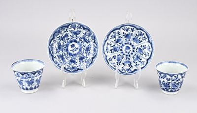 trois assiettes et tasses bleues et blanches posées sur des soucoupes, sur une surface blanche