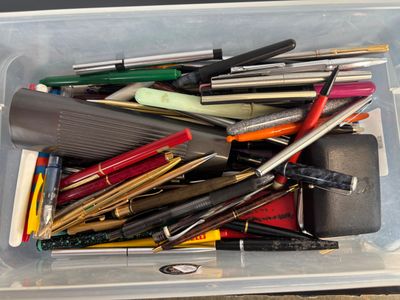many pens and pencils in a container on the table