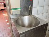 a sink in the middle of a kitchen with a pot on the floor