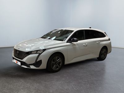 Une voiture blanche est garée dans une pièce blanche au sol noir.