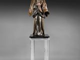 une statue en bronze représentant une femme tenant un enfant dans ses bras, posée sur un socle