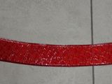 une ceinture rouge avec une boucle argentée sur un parquet