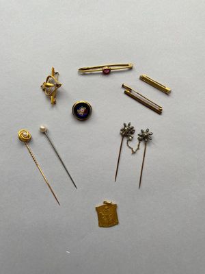 Plusieurs épingles dorées sont disposées en cercle sur une surface blanche.