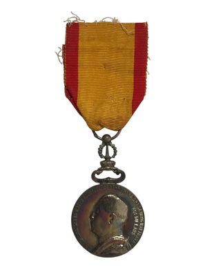 une ancienne médaille avec un ruban rouge sur fond blanc