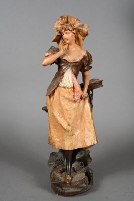 figurine of a woman in a dress and hat holding a bird