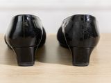 black heels on a wooden table with a white wall in the background