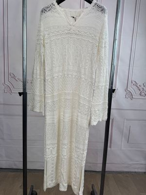 a white sweater dress hanging on a clothes rack in a room