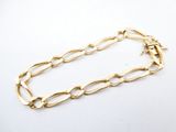gros plan d'un bracelet en chaîne en or sur une surface blanche