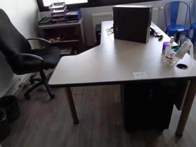 un bureau avec un ordinateur portable et une chaise dans un coin