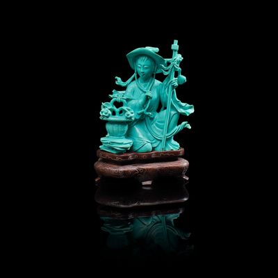 une statuette en jade vert représentant une femme tenant un panier de fleurs, assise sur un rocher
