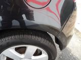 a man standing next to a black car with graffiti on the side of it