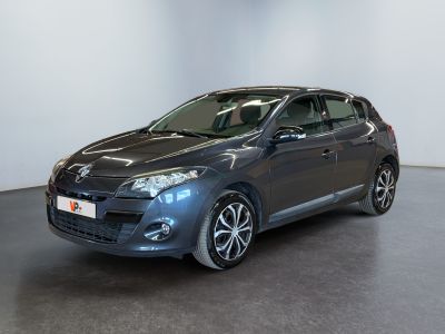 La voiture grise est garée dans une grande pièce au sol noir.