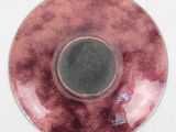 a red plate with a bird on it on a table