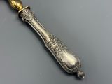 une vieille cuillère en argent avec un manche en or sur un fond gris
