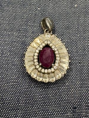 un gros plan d'un pendentif en pierre rouge et diamants posé sur un tissu noir