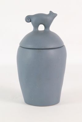 un petit vase bleu avec un ours sur le couvercle
