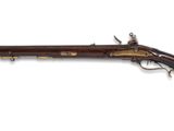 un vieux fusil avec un canon en bois et des garnitures en laiton