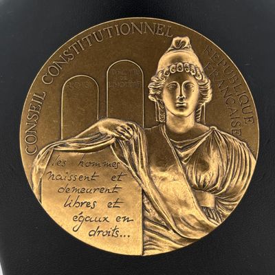un gros plan sur une médaille d'or, avec une femme tenant un livre