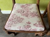a wooden chair with a pink and white floral seat pad