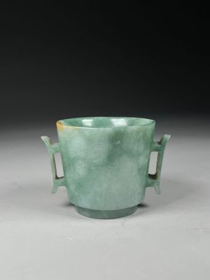 a close up of a green vase with two handles on a table