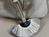 the zipper of a white purse with a tassel hanging from it