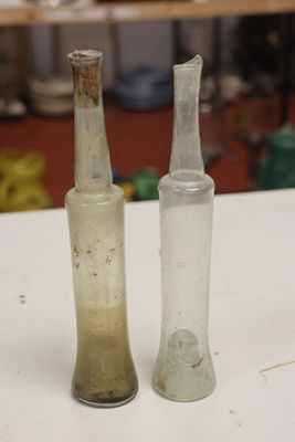two empty glass bottles sitting on a white table