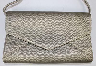 une image représentant un sac à main beige posé sur une surface blanche