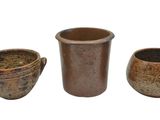 trois vases marron posés les uns à côté des autres sur une surface blanche