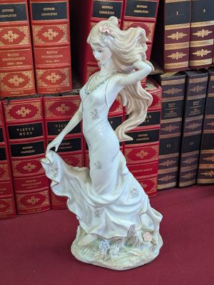 a figurine of a woman holding a dog in front of a stack of books
