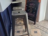 a metal stool sitting in front of a chalk board