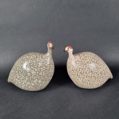 Deux oiseaux en céramique sont posés l'un à côté de l'autre sur une surface noire