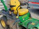 a green lawn mower that is sitting in the dirt
