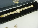 a gold watch in a black box on a white table