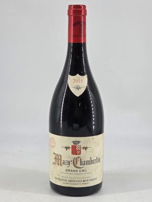 an old bottle of red wine sitting on top of a white table