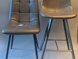 pair of black leather bar stools with metal legs against a white backdrop