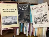 many books that are sitting on top of a book shelf