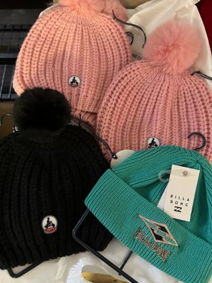 several hats are sitting on top of a table with a laptop in the background