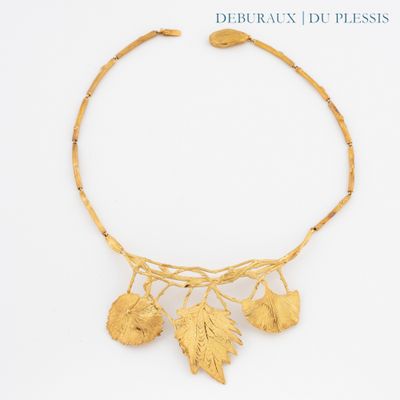 un gros plan d'un collier en or orné de feuilles