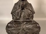 an old statue of a woman sitting on top of a bowl