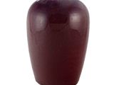 un vase rouge posé sur une surface blanche