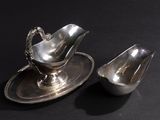a silver sauce boat and a silver sauce boat on a black table