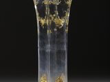 un vase en verre orné de motifs dorés, posé sur une table