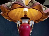 a lamp that is on a table with a red vase on it