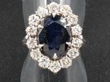 gros plan d'une bague avec une pierre bleue entourée de diamants blancs