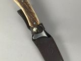 a close up of a knife on a white surface with a leather sheath