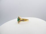 an image of a gold ring with a green stone and diamonds