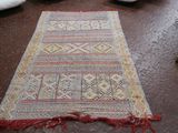 un tapis posé par terre, à côté d'une paire de chaussures posée par terre