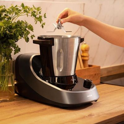 une femme en train de mettre quelque chose dans un mixeur posé sur un plan de travail de cuisine